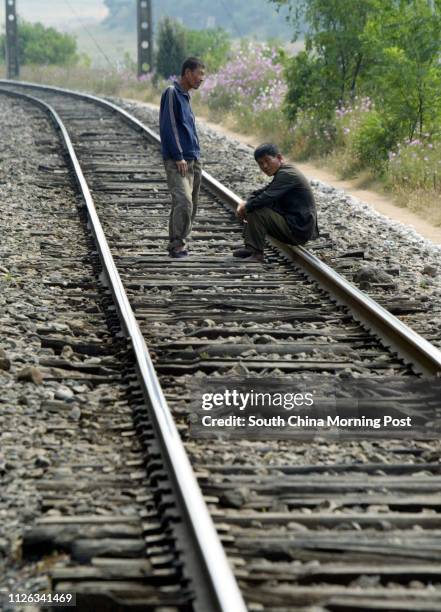 Pair of unemployed North Korean men walk beside a train line in the north-western part of the country. Poverty and famine are still rife in the...