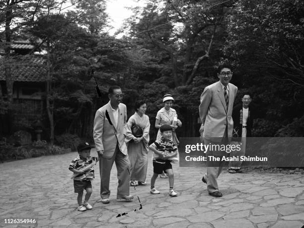 Prime Minister Nobusuke Kishi holds hand of his grandson Shinzo Abe walking with his wife Ryoko , son-in-law and lawmaker Shintaro Abe , his wife...