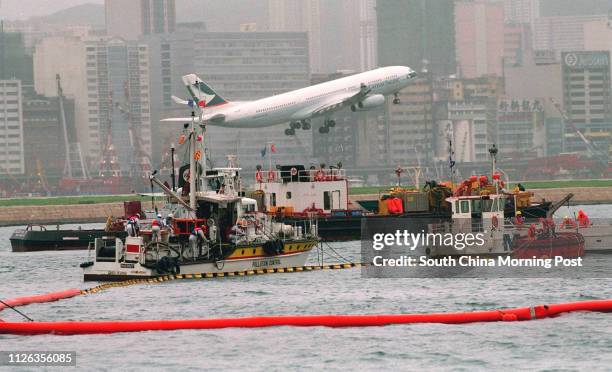 An aeroplane is taking off the Kai Tak Airport when an oil pollution control is exercising at Kowloon Bay. Photo by Mark Ralston