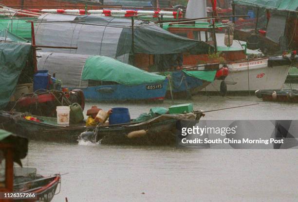 A FISHERMAN BAILS OUT HIS BOAT AFTER HEAVY RAIN.