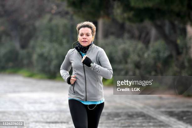 adult woman running early morning at a sidewalk - fleece stoff stock-fotos und bilder