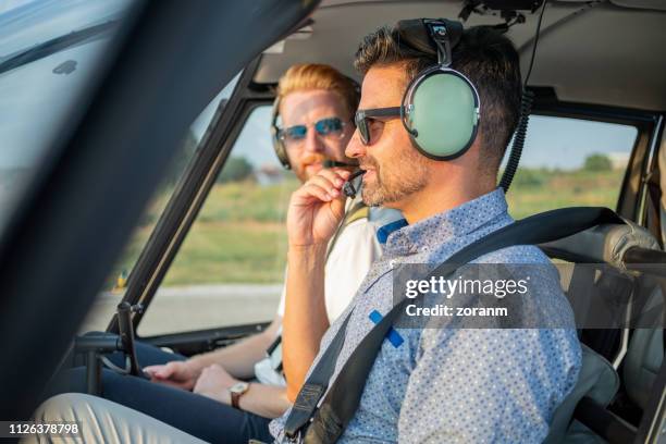 passenger holding and testing headset microphone in helicopter - helicopter pilot stock pictures, royalty-free photos & images