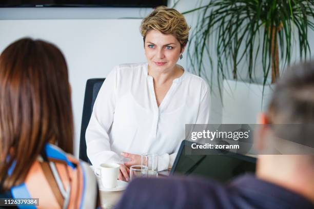 zakenvrouw collega kijken en luisteren met belangstelling - 30 40 woman stockfoto's en -beelden