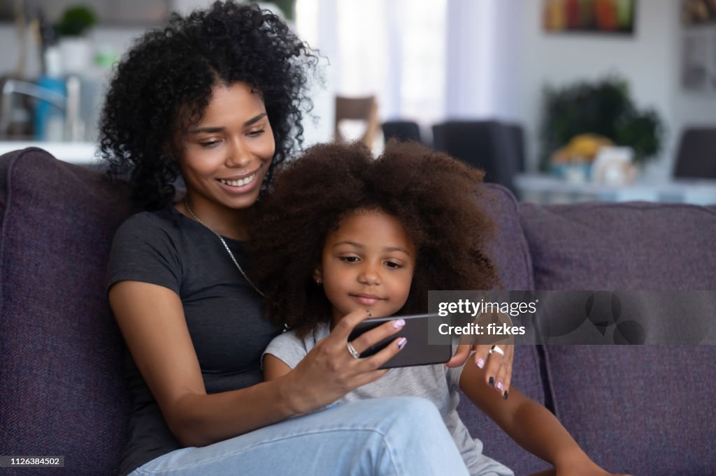 Niña de mamá y el niño de raza mixta hacer video llamada en el teléfono móvil