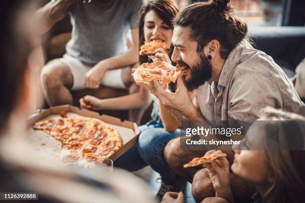 happy man eating pizza with his friends at home. - sharing pizza stock pictures, royalty-free photos & images