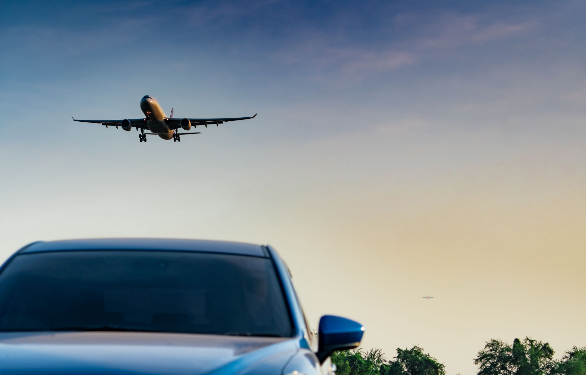Commercial airline. Passenger plane landing approach blue SUV car at airport with blue sky and clouds at sunset. Arrival flight. Vacation time. Happy trip. Airplane flying on bright sky. Car parked. Commercial airline. Passenger plane landing approach blue SUV car at airport with blue sky and clouds at sunset. Arrival flight. Vacation time. Happy trip. Airplane flying on bright sky. Car parked.