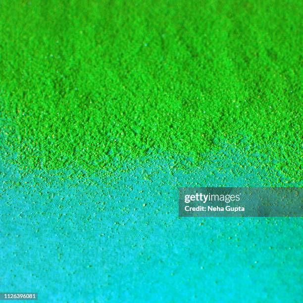 splash of green powder paint on a turquoise background - vernice in polvere foto e immagini stock