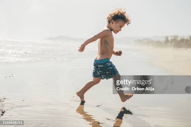 jongen draait op het strand - alleen één jongen stockfoto's en -beelden