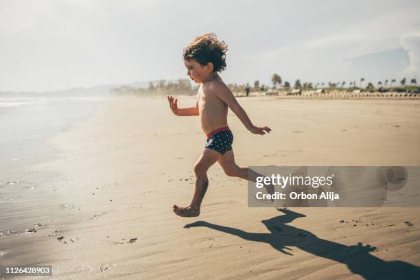 jongen draait op het strand - alleen één jongen stockfoto's en -beelden