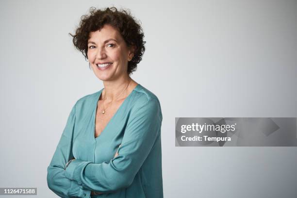 mid adult businesswoman headshot on grey background. - 50 years in business stock pictures, royalty-free photos & images