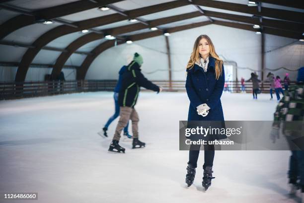 beautiful blond hair girl in a blue coat enjoys skating on ice indoor. - jan 19 stock pictures, royalty-free photos & images