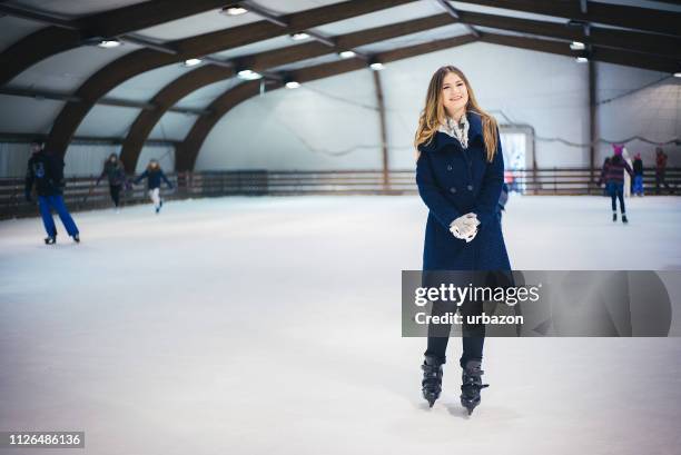 beautiful blond hair girl in a blue coat enjoys skating on ice indoor. - jan 19 stock pictures, royalty-free photos & images