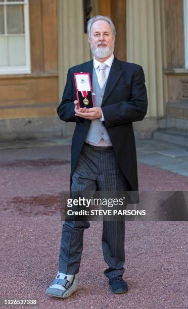 British choreographer Richard Alston poses with his medal after being appointed as a Knights Bachelor at an investiture ceremony at Buckingham Palace...