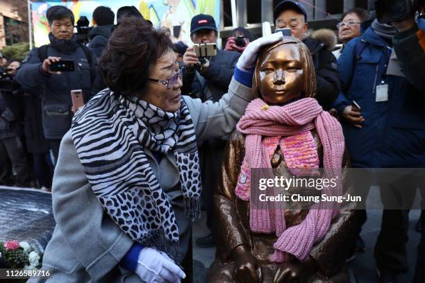 Lee Yong-Soo, a former 'comfort woman,' who served as a sex slave for Japanese troops during World War II, sits next to a comfort woman statue during...