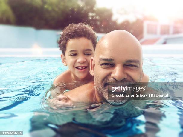 father and son on vacation playing in the pool on a sunny day - family pool foto e immagini stock