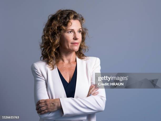 businesswoman with arms crossed looking away - executive board portrait session stock pictures, royalty-free photos & images