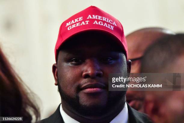 Man wearing a "Make American Great Again" cap awaits the start of a White House reception in honor of National African American History Month hosted...