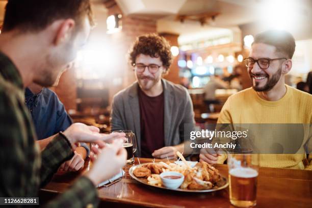 treffen mit den besten freunden in einer bar - chicken wing stock-fotos und bilder