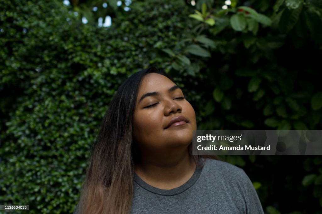 Young Mixed Race Woman Closes Eyes in Foliage