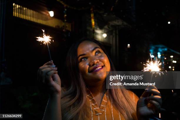 young mixed race woman celebrating with sparklers - voluptuous stock pictures, royalty-free photos & images