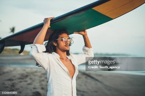 ragazzo con tavola da surf sulla spiaggia - capelli lunghi foto e immagini stock