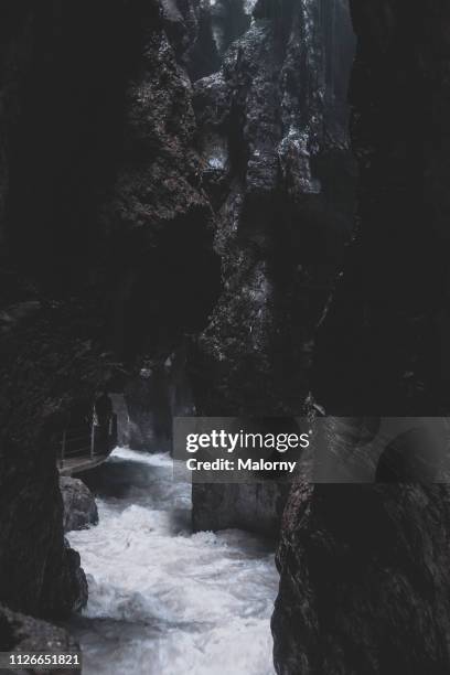 small stream running through dark gorge or crevice. rocks in the foreground and background - running mate fotografías e imágenes de stock