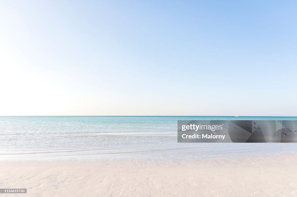Turquoise colored sea and beach with clear blue sky.