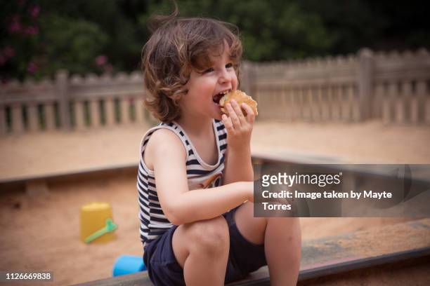 toddler having a sandwich at the park - toddler eating sandwich stock-fotos und bilder