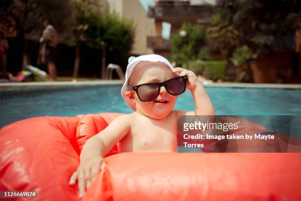 baby boy wearing sunglasses at the pool - humor fotografías e imágenes de stock