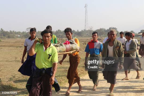 This photo taken on February 21, 2019 shows residents carrying a body of an ethnic Rakhine woman for burial in Rathedaung township after fresh...