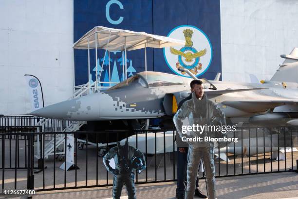 An attendee poses for a photograph in front of a Saab AB Gripen E smart fighter aircraft during the Aero India air show at Air Force Station...