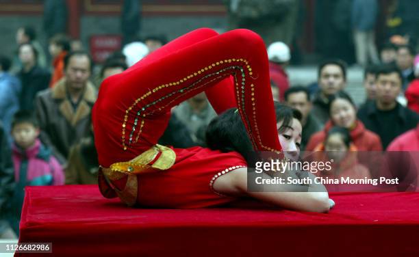 Young Chinese contortionist performs for a crowd at the Dongyue Temple Fair in Beijing, China. The fair at this temple is reputed to have an...