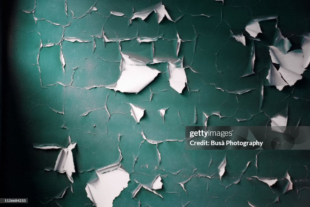 Paint peeling off a plaster wall in an interior setting