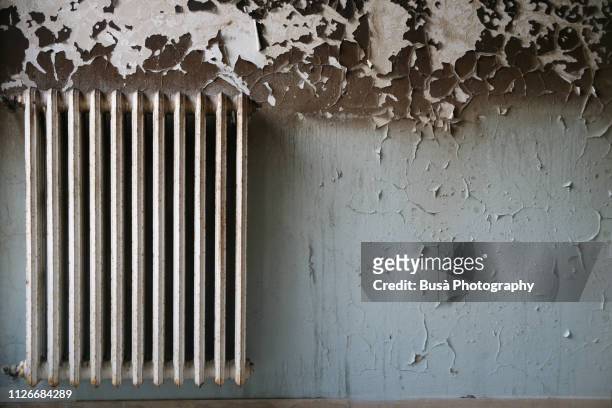 radiator and wall with peeling paint in interior setting - aspergillus stockfoto's en -beelden