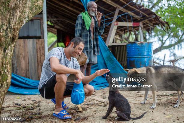 Kurdish asylum seeker, Ari Sirwan, 26 years old, plays with a dog while he is on a day trip to a neighboring island to Manus. The human cost of...