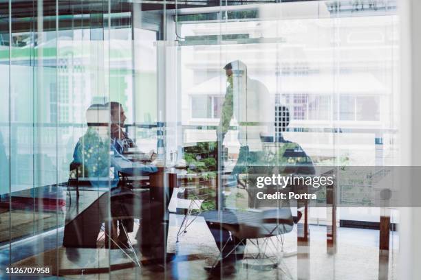 compañeros de trabajo en la reunión en la oficina - fotografiado a través de una ventana fotografías e imágenes de stock