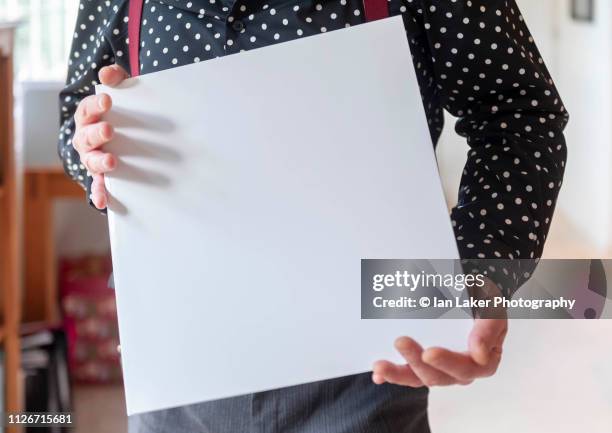 littlebourne, canterbury, england. 20 january 2019. plain white vinyl record or album cover being displayed and held by person in a domestic setting. - album cover stock-fotos und bilder