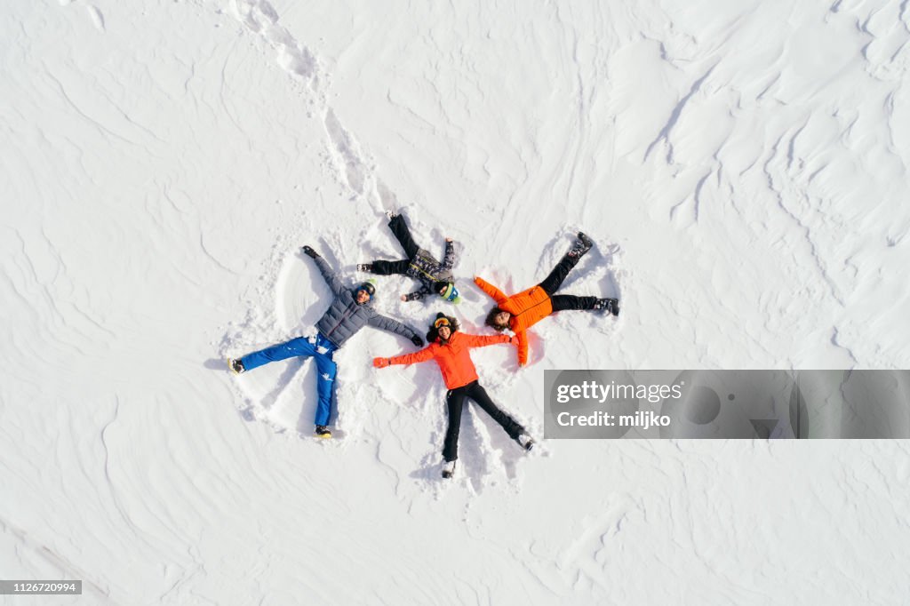 Lycklig familj liggande på rygg på snö