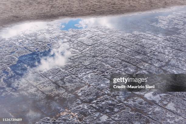 reflection in a puddle of clouds in the rain - lastricato stock-fotos und bilder