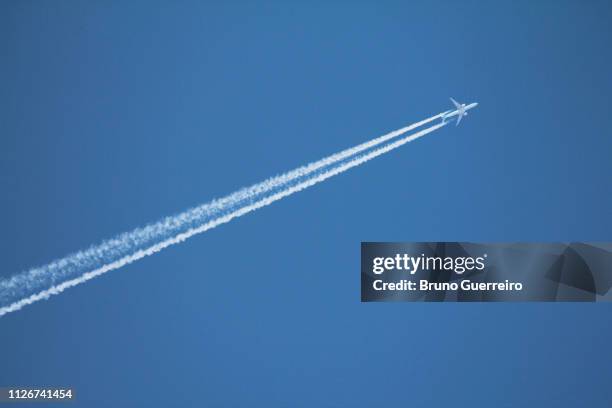 airplane leaving vapor trail behind against blue sky - trainee photos et images de collection