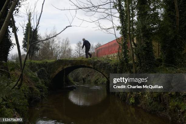 Man crosses a small bridge which separates Northern Ireland, in the United Kingdom and the Republic of Ireland on February 15, 2019 in Muff, Ireland....