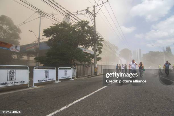 February 2019, Colombia, Medellín: People walk through the smoke in a blocked street after the demolition of the house of Pablo Escobar. 1,500 people...