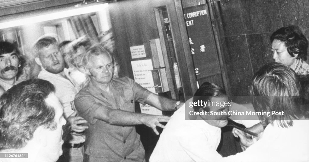 Black and white photo.  An ICAC official has his tie yanked when some police officers attempted to break into the ICAC office at Hutchison House.  More than 2000 police officers gathered outside the Police Headquarters earlier in protest against what they