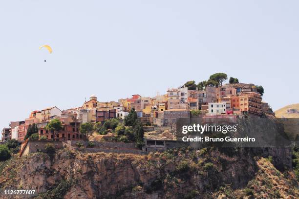 paraglider flying above castelmola village perched on top of rock - castelmola stock-fotos und bilder