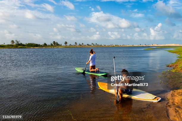 dois jovens adultos praticando levantar paddle - desportos aquáticos - oasis - conexão com a natureza - atividade de relaxamento - fortaleza - rep - fotografias e filmes do acervo