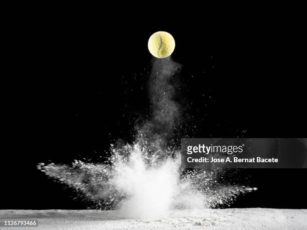 impact and rebound of a ball of tennis on a surface of land and powder on a black background - dribbling sports stock-fotos und bilder