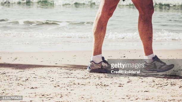 active senior walking on the sandy beach - knee replacement surgery stock-fotos und bilder