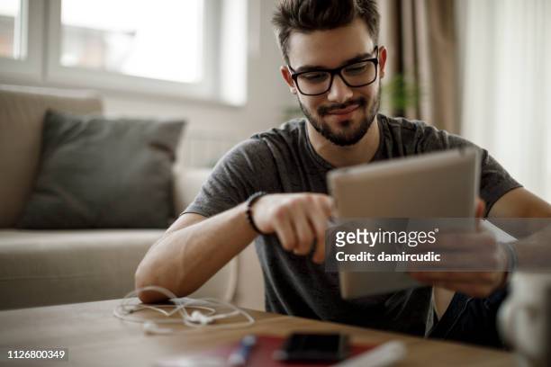 junger mann mit digitalen tablet zu hause - e reader stock-fotos und bilder