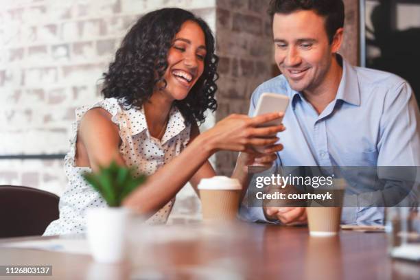 businessman and businesswoman looking at a mobile phone. - casual work men and women laughing stock pictures, royalty-free photos & images