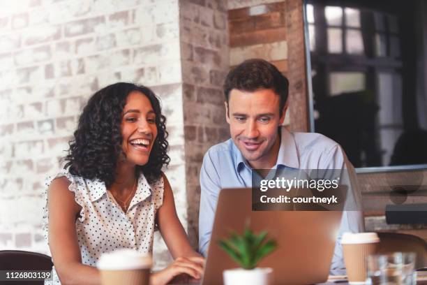businessman and businesswoman in a meeting with a laptop computer. - casual work men and women laughing stock pictures, royalty-free photos & images